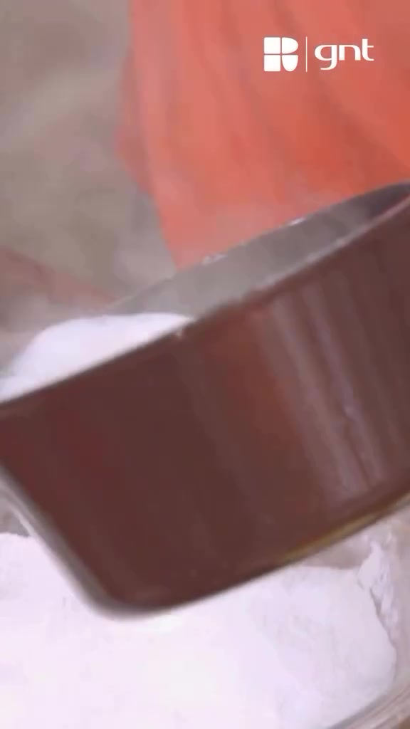 Líquido quente sendo despejado sobre os polvilhos, com marca d'água GNT preservada.