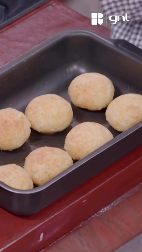 Pães de queijo dourados em assadeira, com marca d'água GNT preservada.