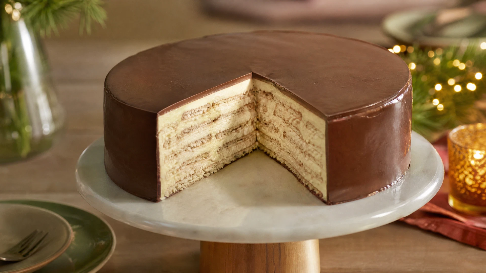 Fatia de torta alemã gelada com creme, biscoitos e cobertura de chocolate.
